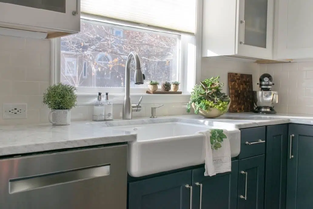 3 Ways to Style your Farmhouse Sink. Farmhouse sink styled with green accents in a kitchen remodel