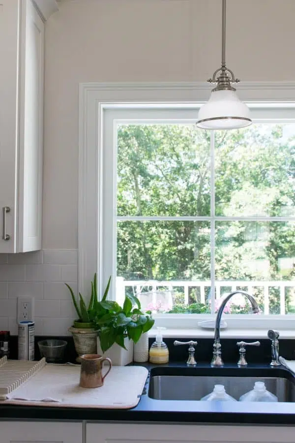 White kitchen cabinets and Kitchen sink with black counters and widespread kitchen faucet.