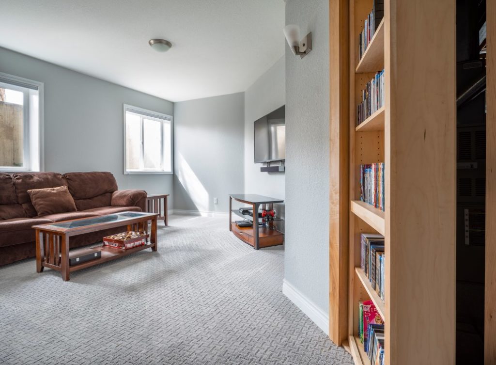 Basement living room with stonington gray walls and secret bookshelf door