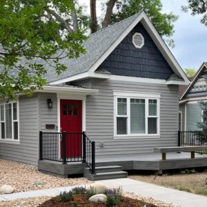A gray and dark gray home exterior with red door
