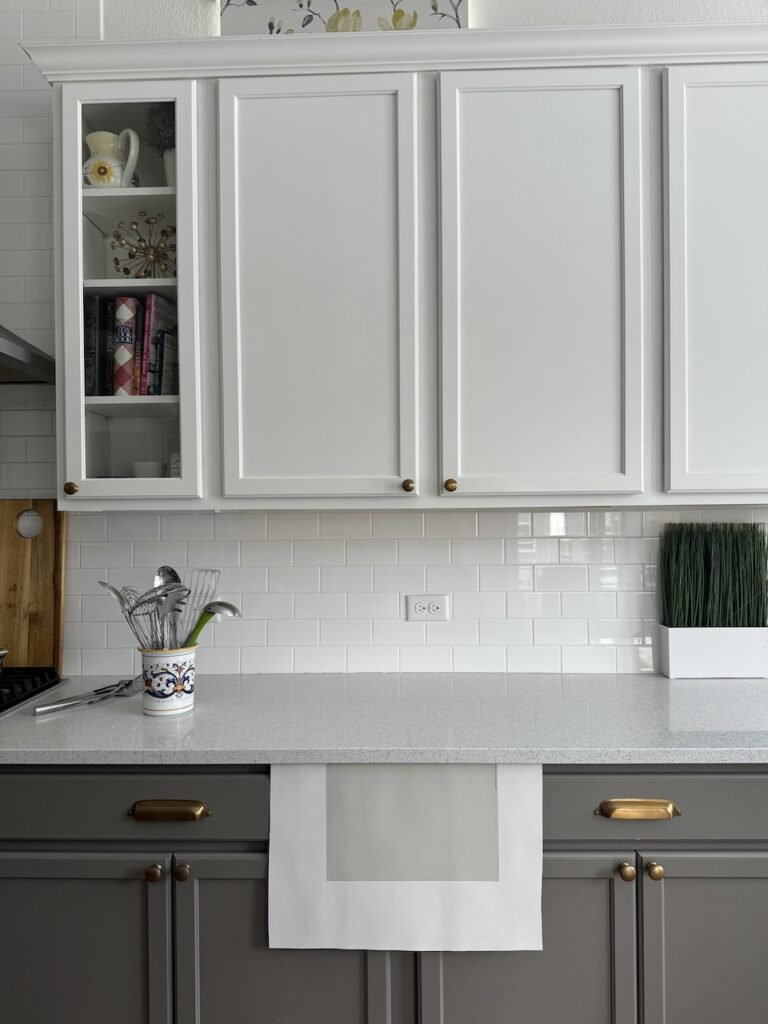 A kitchen with white and gray finishes is shown with a gray paint color swatch for testing.