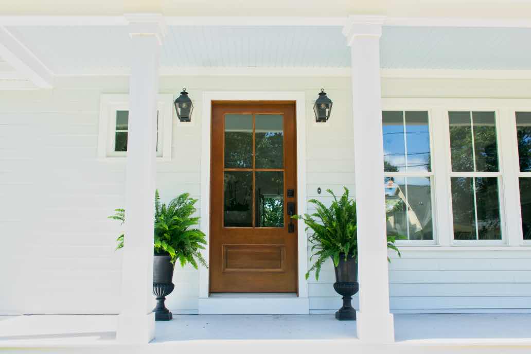 house with farmhouse white paint color and wood front door