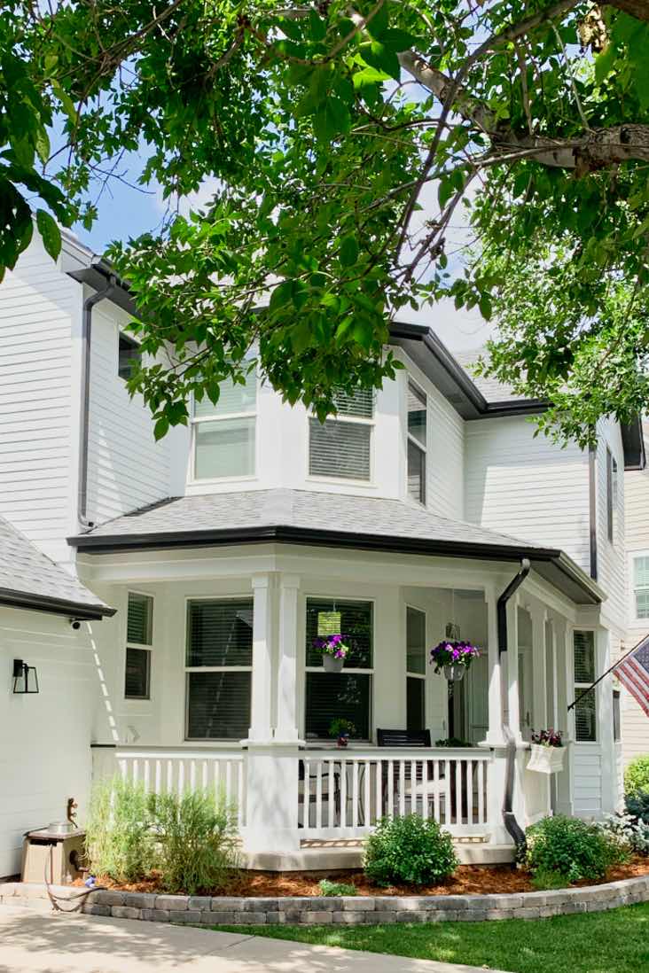 house with farmhouse white paint color, white picket fence and American flag
