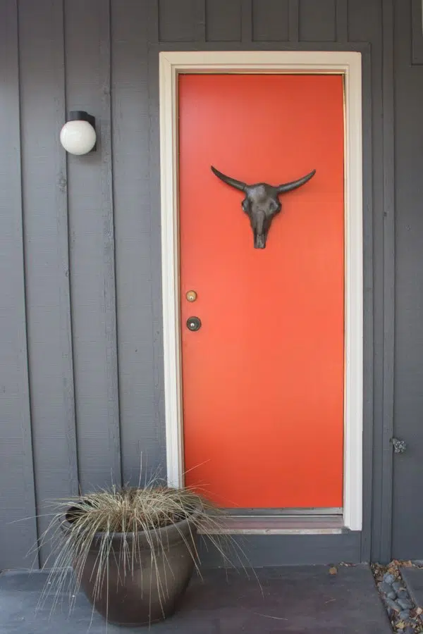 Orange front door with white trim and blue siding