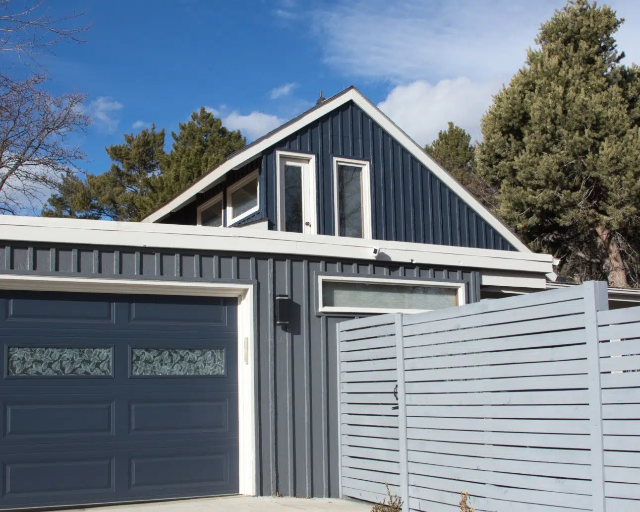 Dark blue and medium blue house with white trim and dark blue garage door 