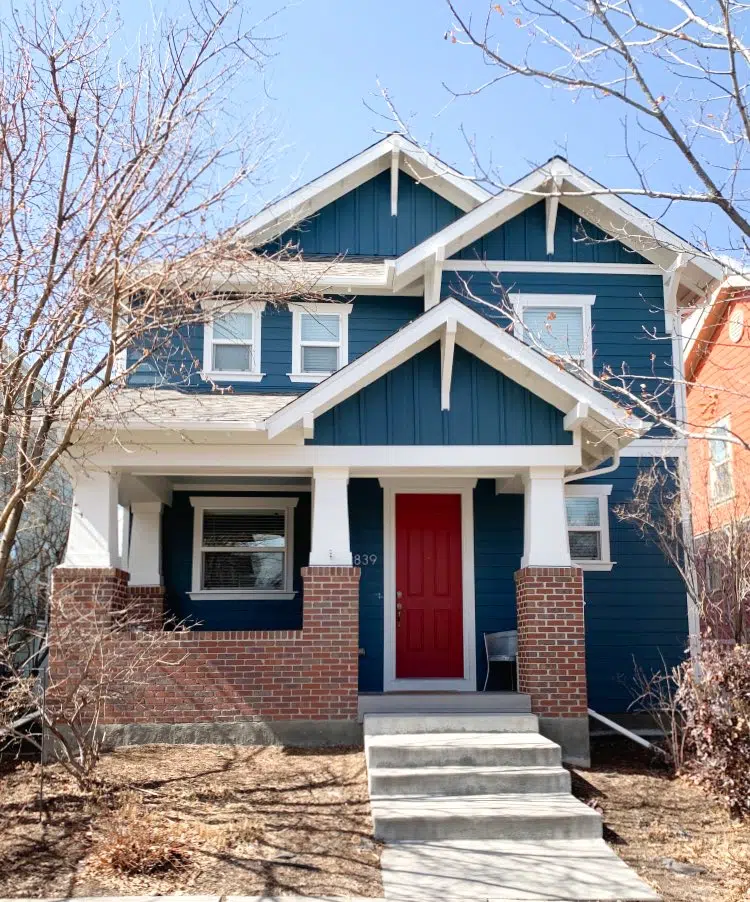 Red brick house with Newburg Green siding Classic Gray trim and Caliente red front door