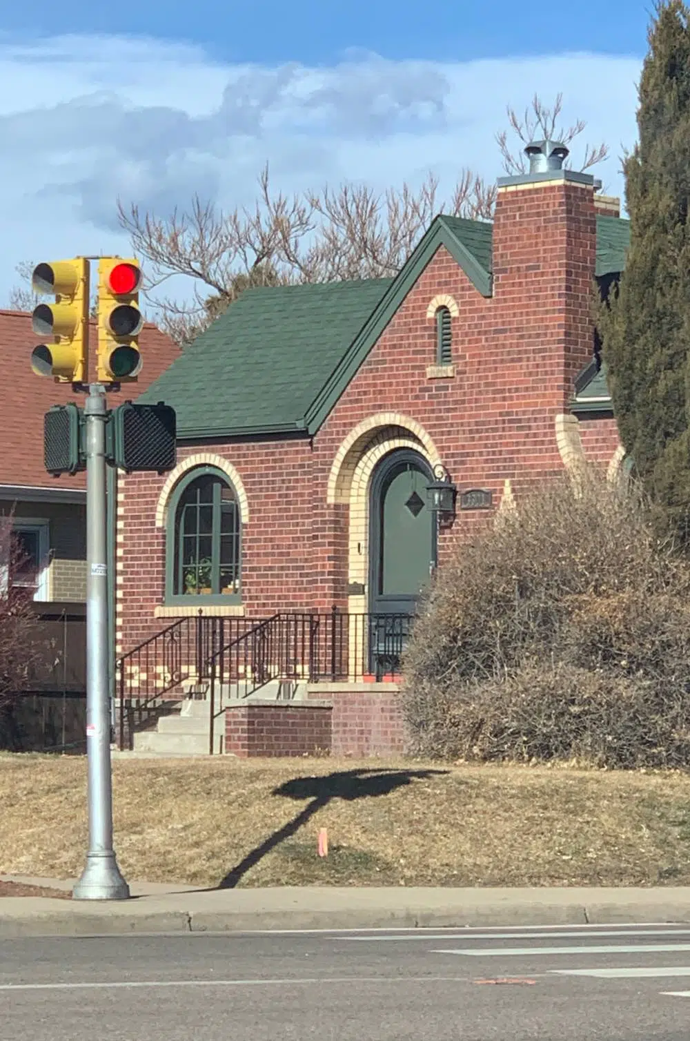 Red brick house with green roof and matching trim