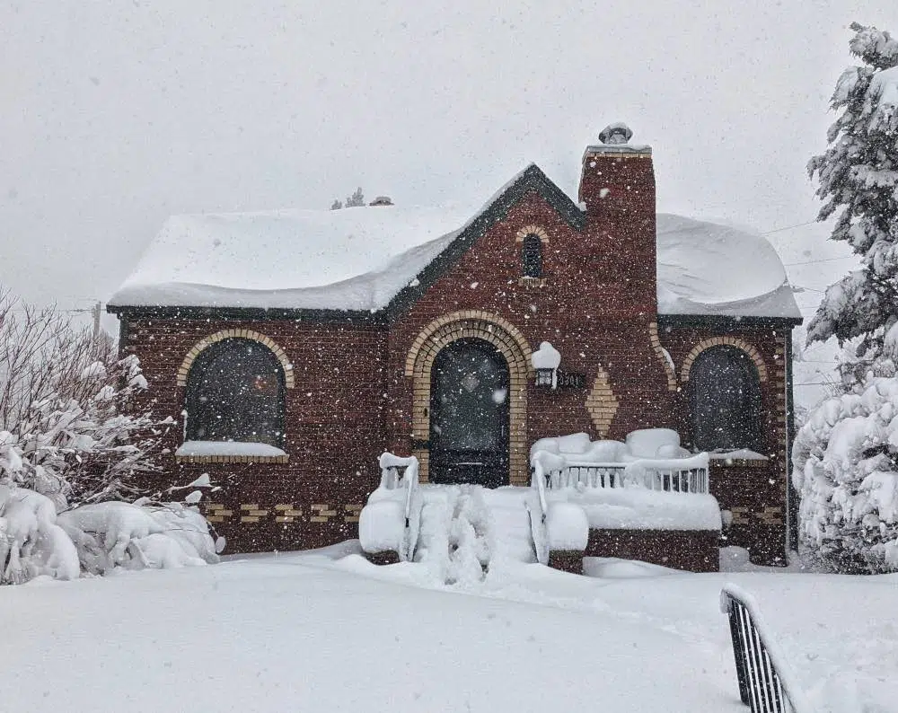 Red brick house in the snow with SW Pewter Green paint color.