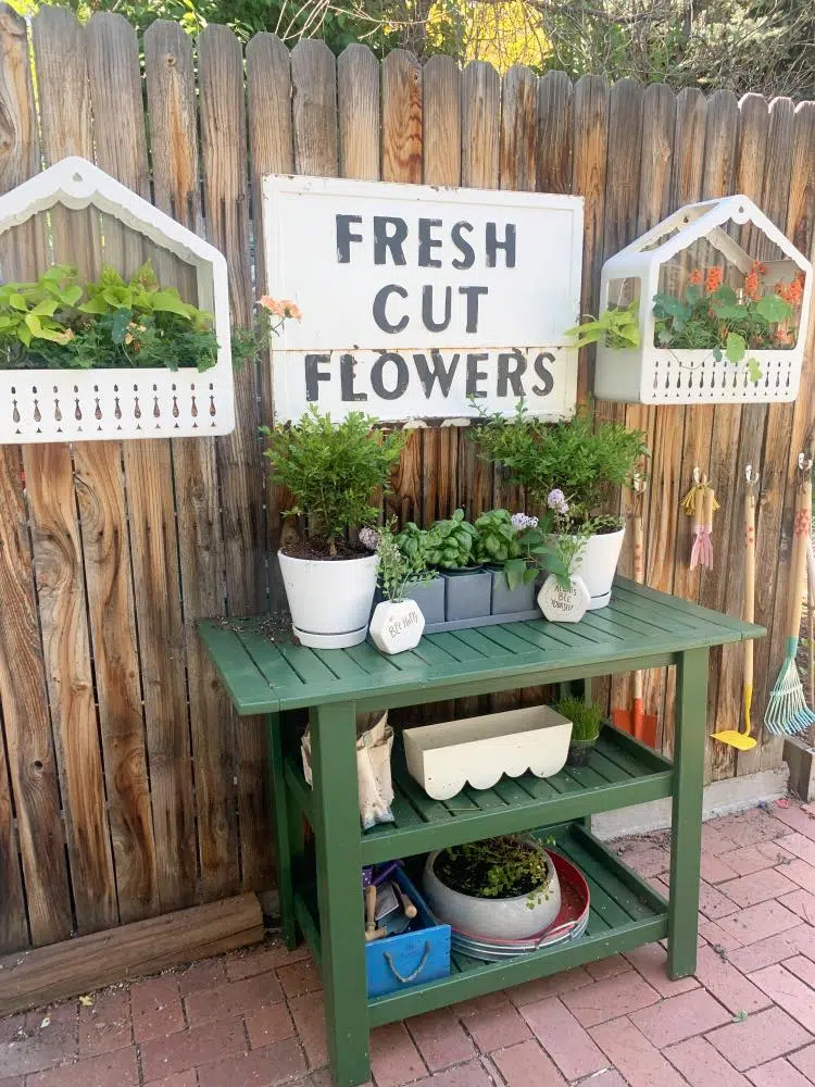 Red brick patio with flowers and green plant stand