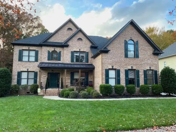 Brick house with Benjamin Moore Salamander Shutters and front door