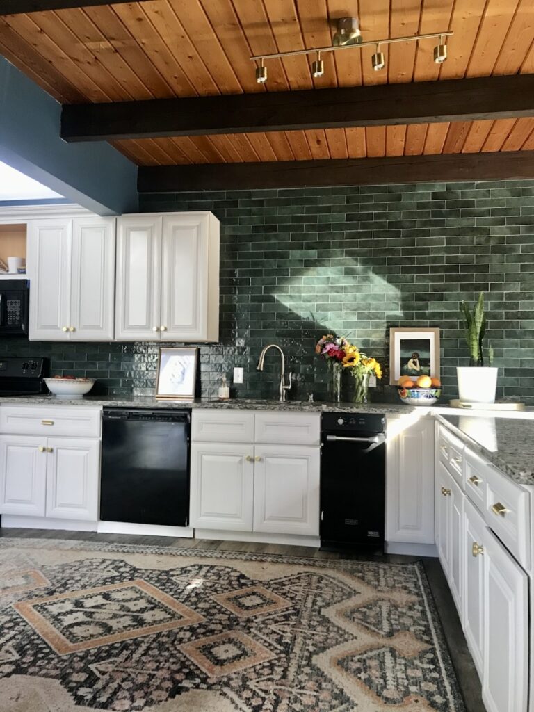 Kitchen with green backsplash and Balboa White Cabinets with warm wood ceiling