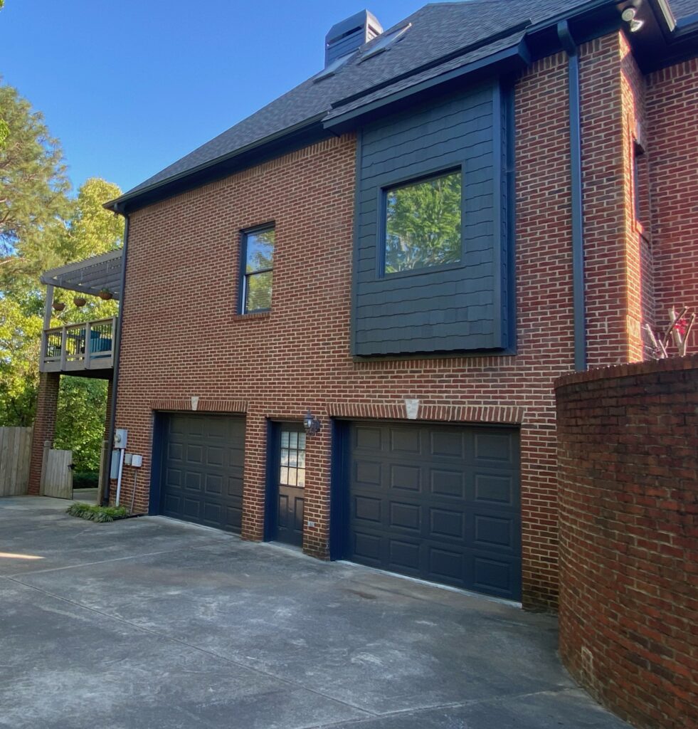 A red brick home with black painted garage doors and trim paint.