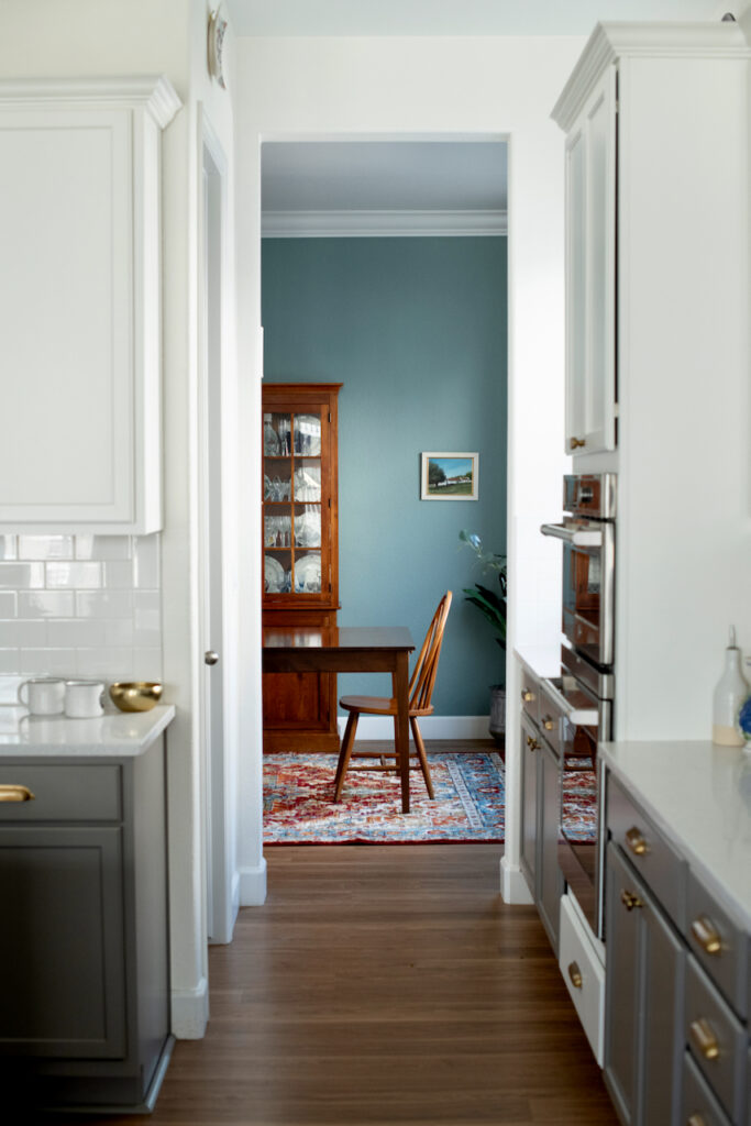 A view of an Oval Room Blue dining room through a white and gray kitchen.