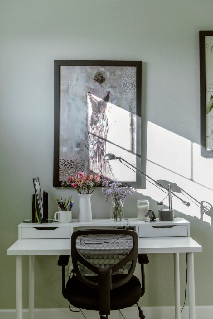 A white desk and black-framed art piece on a wall painted with Farrow & Ball Cromarty