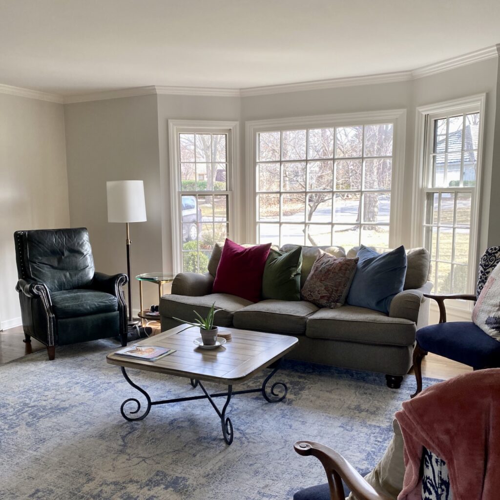 A living room with a large window and gray coach is painted with Benjamin Moore Pale Oak paint