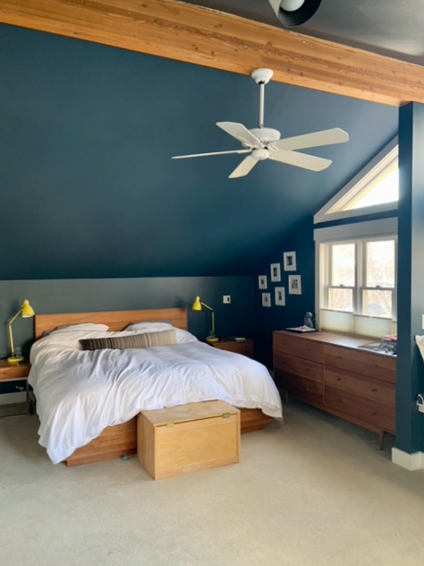 A Farrow & Ball Hague Blue bedroom with large windows and a natural wood beam with natural wood furniture.