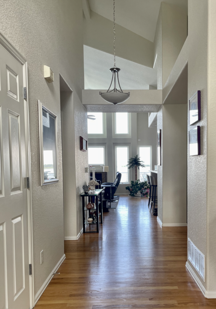 A hallway and living room are painted with Benjamin Moore Gray Mist paint in this whole house paint color scheme