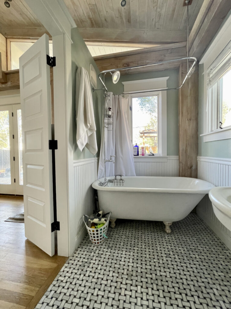 A Farrow & Ball Teresa's Green bathroom with white clawfoot tub and wooden ceiling