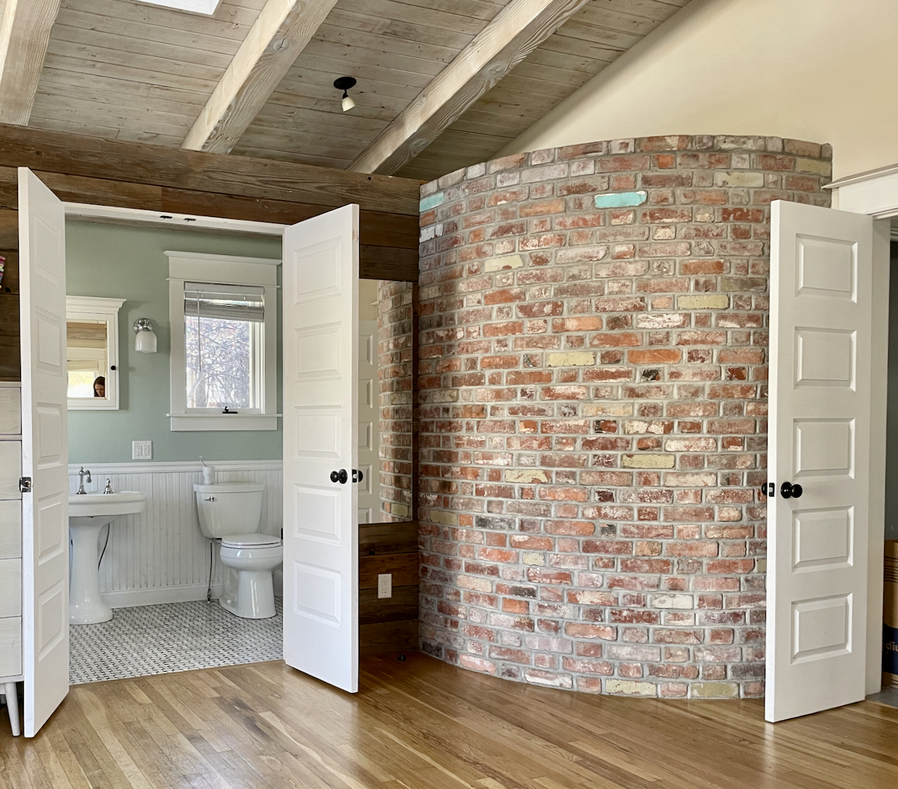A cottage room with brick accent wall and Teresa's Green bathroom wall