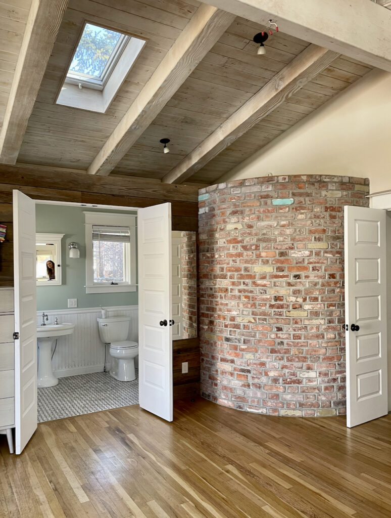 A large space with wooden ceiling, brick accent wall and Teresa's Green paint on bathroom walls