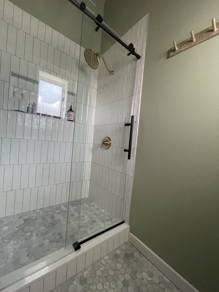 A modern white and gray tile shower stands next to a wall painted with Vert de Terre