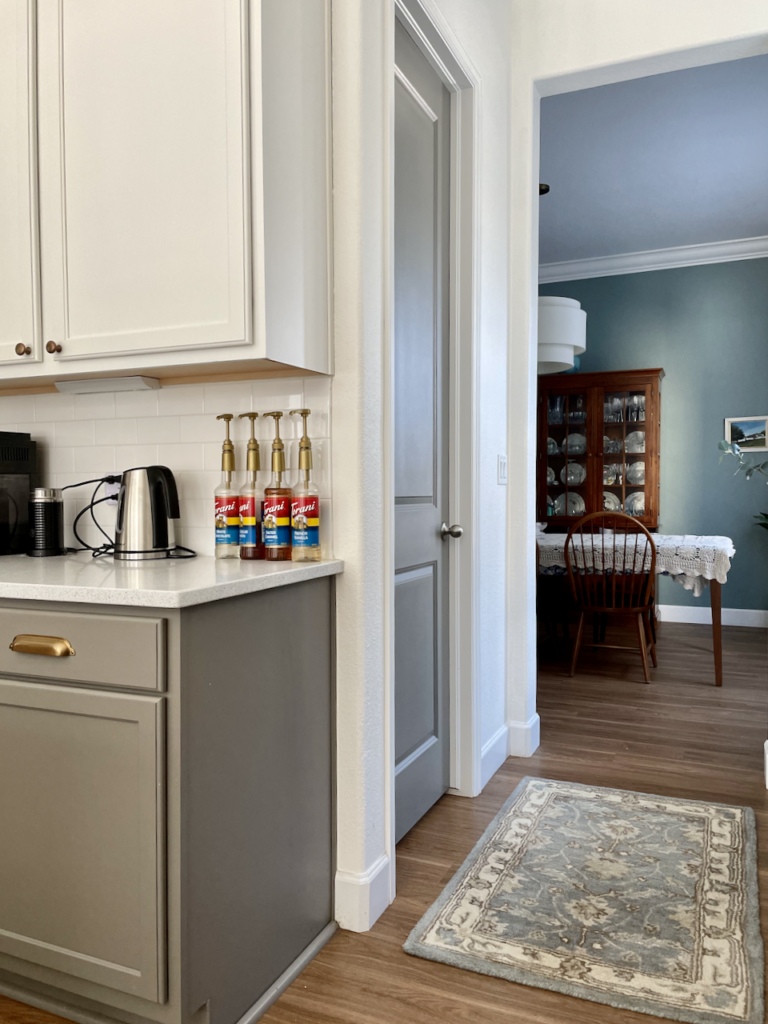A gray painted pantry door with matching gray kitchen cabinets