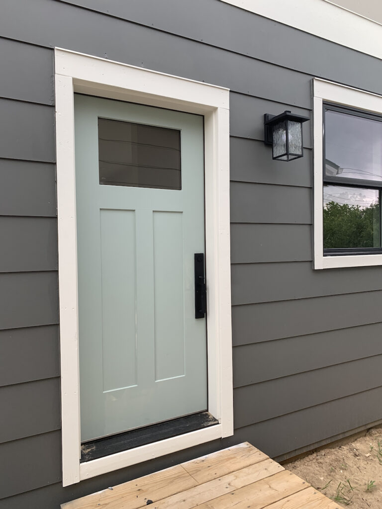 A light teal front door paired with white trim and gray siding.