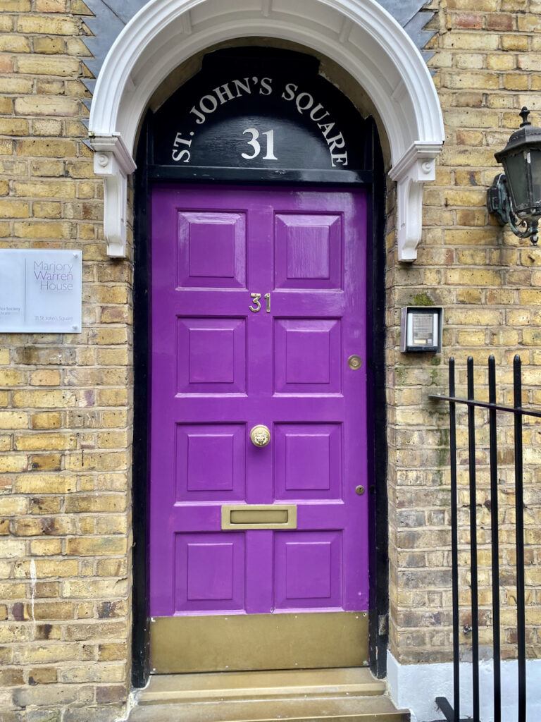 A bright purple front door on a light brick house.