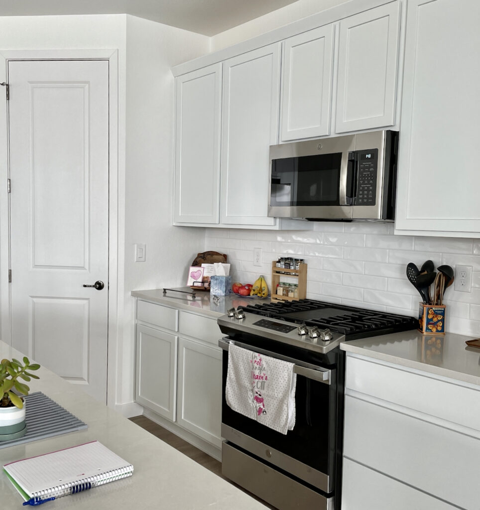 Kitchen painted with SW Pure White walls and doors, with cooler white cabinets and gray countertops.