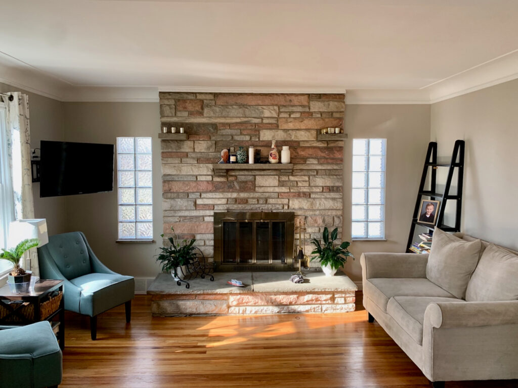 A living room with large stone fireplace and Benjamin Moore Revere Pewter paint.