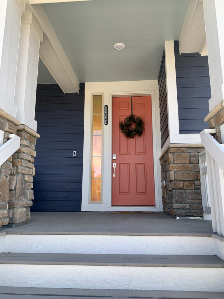 A home is painted with Charcoal Blue and paired with a Quite Coral front door.