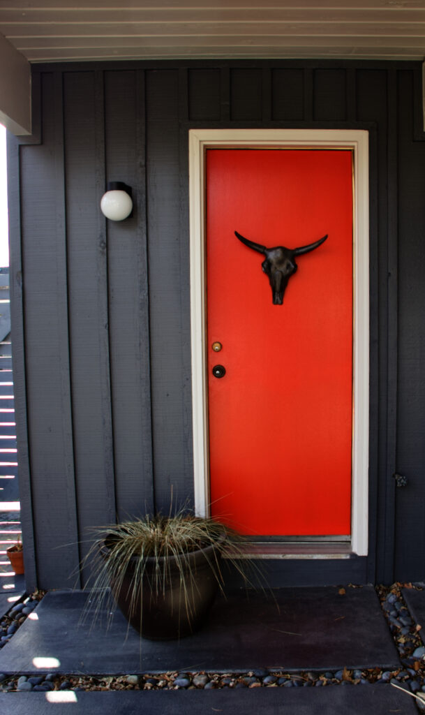A bright red front door painted with BM Redstone with gray siding.