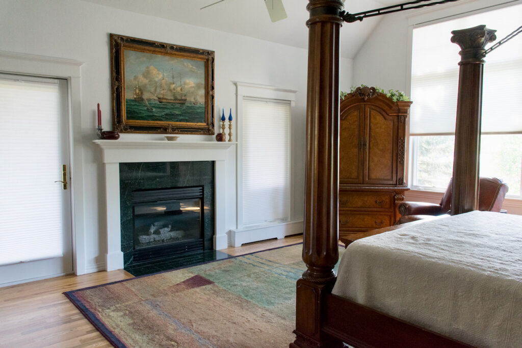 This Sherwin-Williams Extra White bedroom features a fireplace and wood bed.