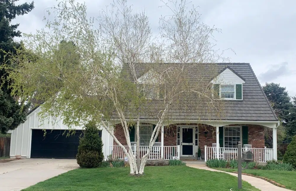 A home is painted with SW Greek Villa exterior paint with red brick accents.