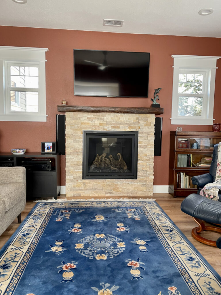 A living room is painted with BM Giant Sequoia paint and features a stacked stone fireplace.