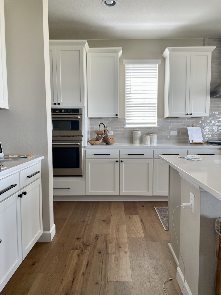 A kitchen painted with SW Accessible Beige and SW Pure White cabinets.
