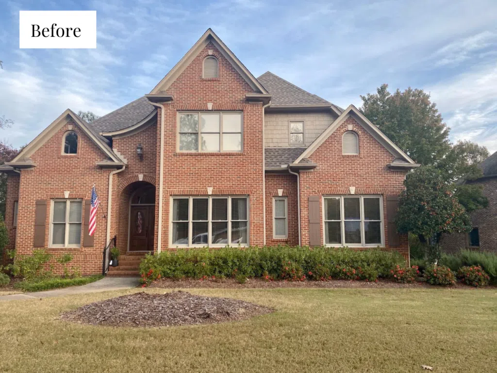 A red brick home with beige trim before paint color transformation