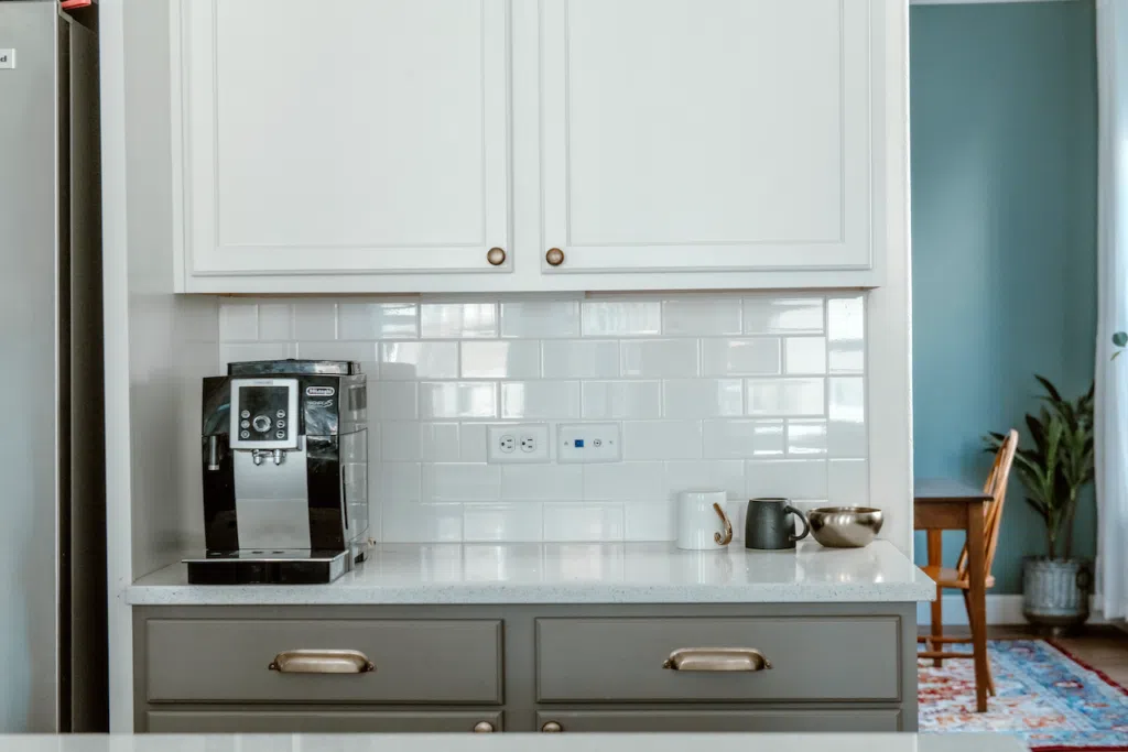 A dining room painted with Farrow & Ball Oval Room Blue paint is pictured next to BM Chelsea Gray and Simply White tuxedo kitchen cabinets. 