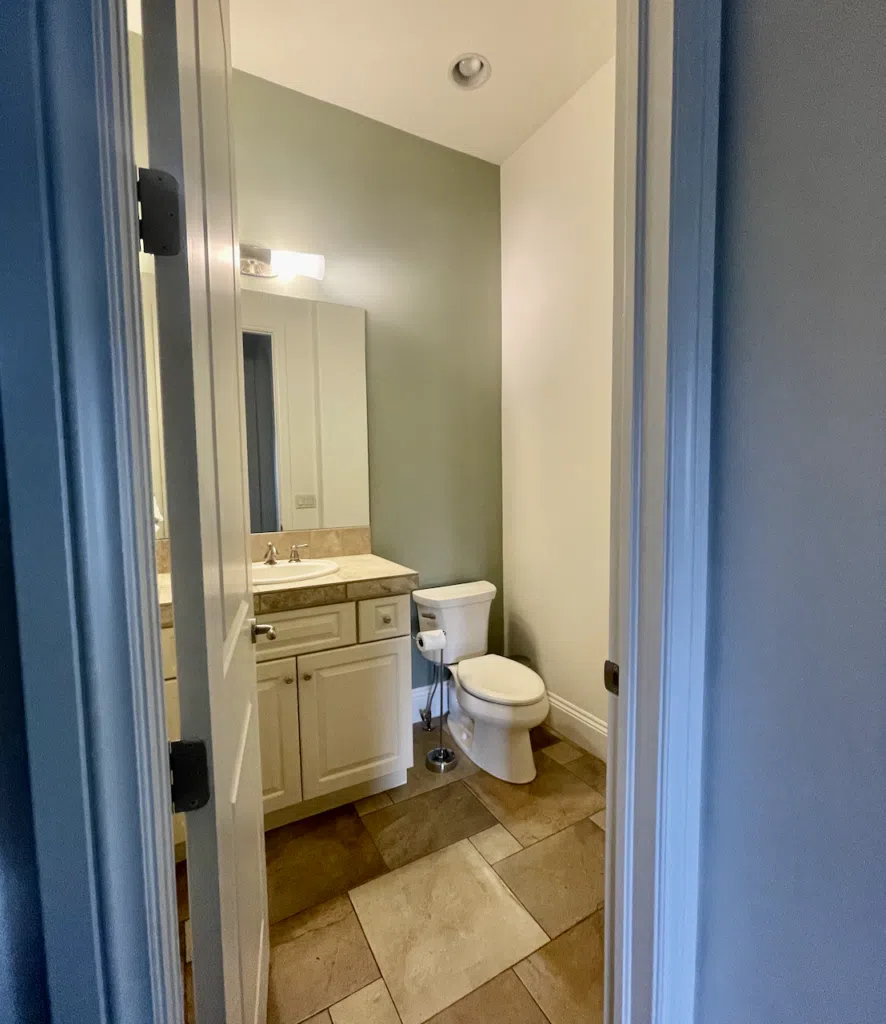 A bathroom painted with BM Swiss Coffee paint and a sage green accent wall. 