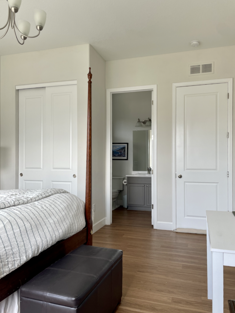 A bedroom and bathroom are painted with Sherwin-Williams Mortar paint