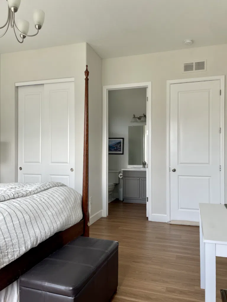 A bedroom and bathroom are painted with Sherwin-Williams Mortar paint