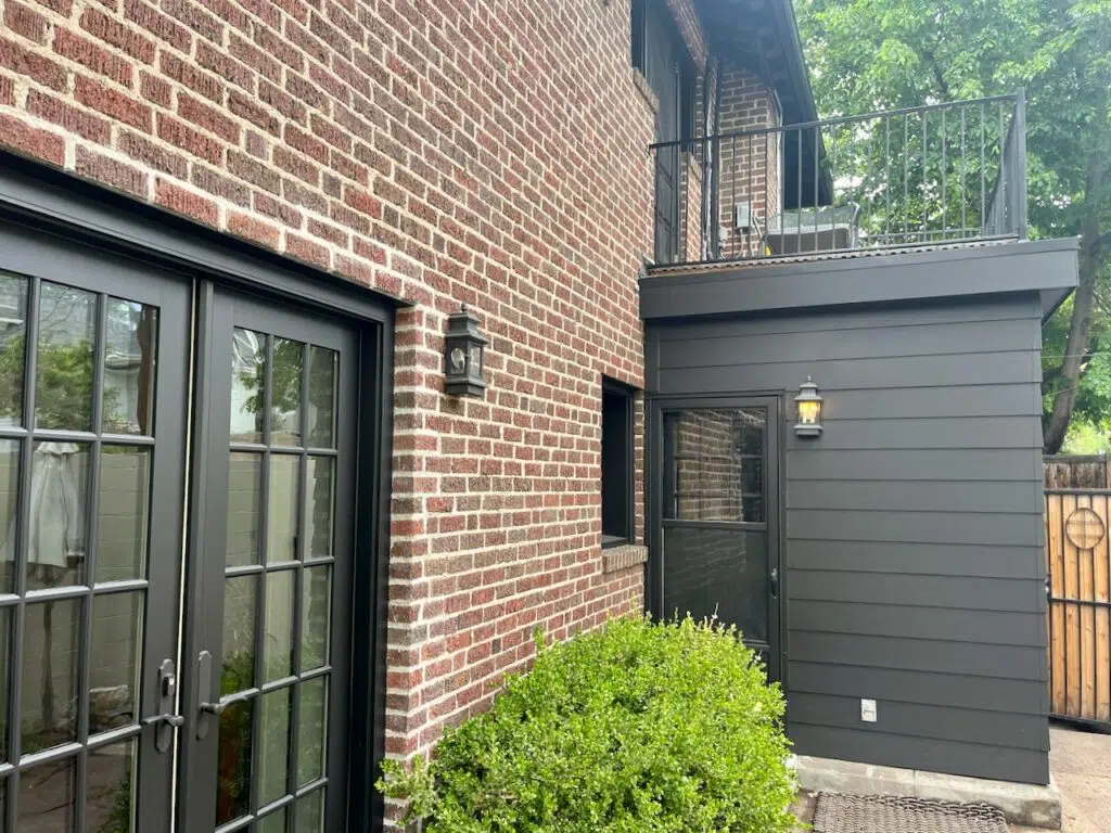 A red brick home with black trim paint is pictured. 