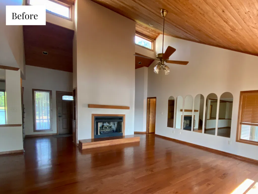 A living room with high ceilings and a fireplace wall with a wood ceiling