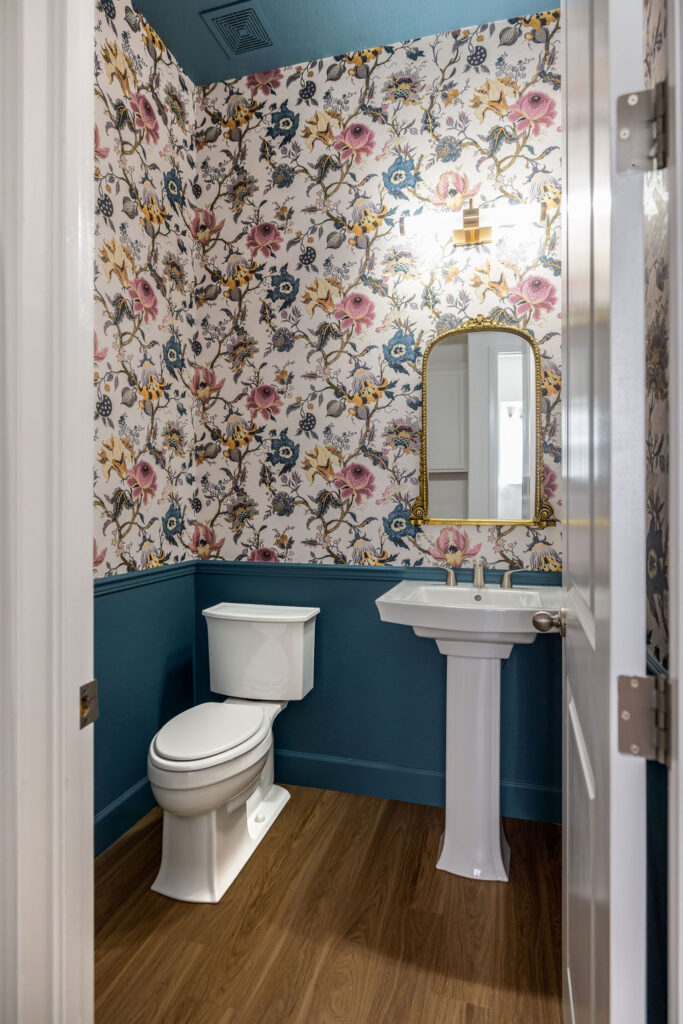 A small powder room with wallpaper, wainscoting and BM Bella Blue paint