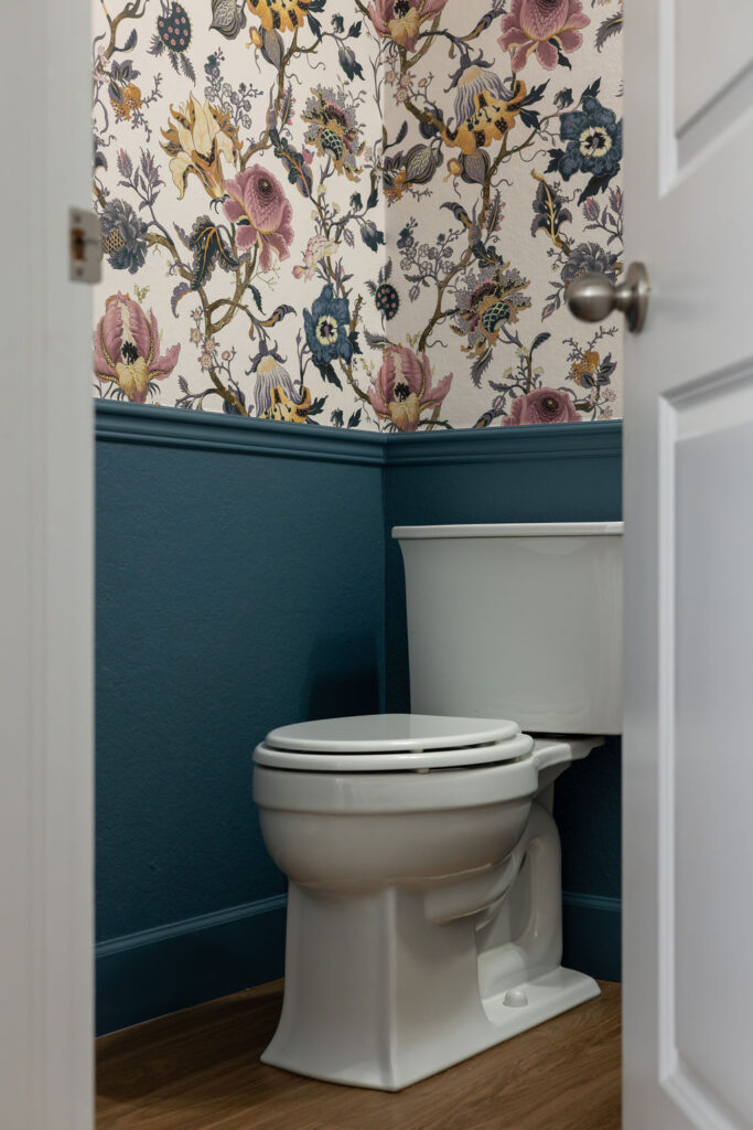 A BM Bella Blue powder room with blue wainscoting and floral wallpaper.
