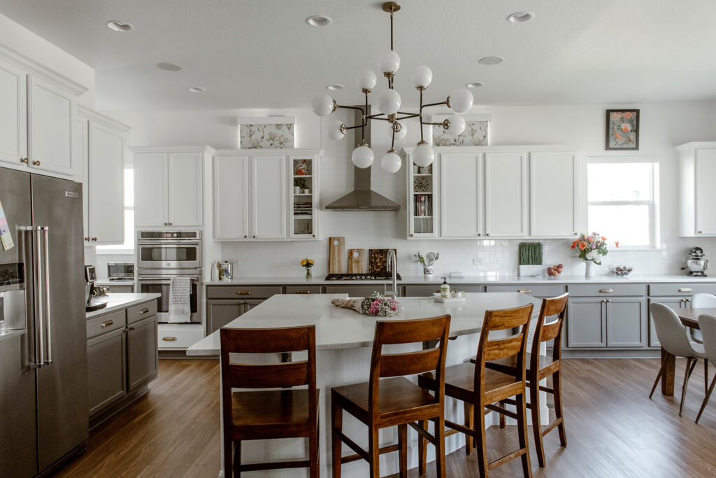 A BM simply white kitchen features tuxedo kitchen cabinets with BM Chelsea Gray lowers and SW Pure White uppers.