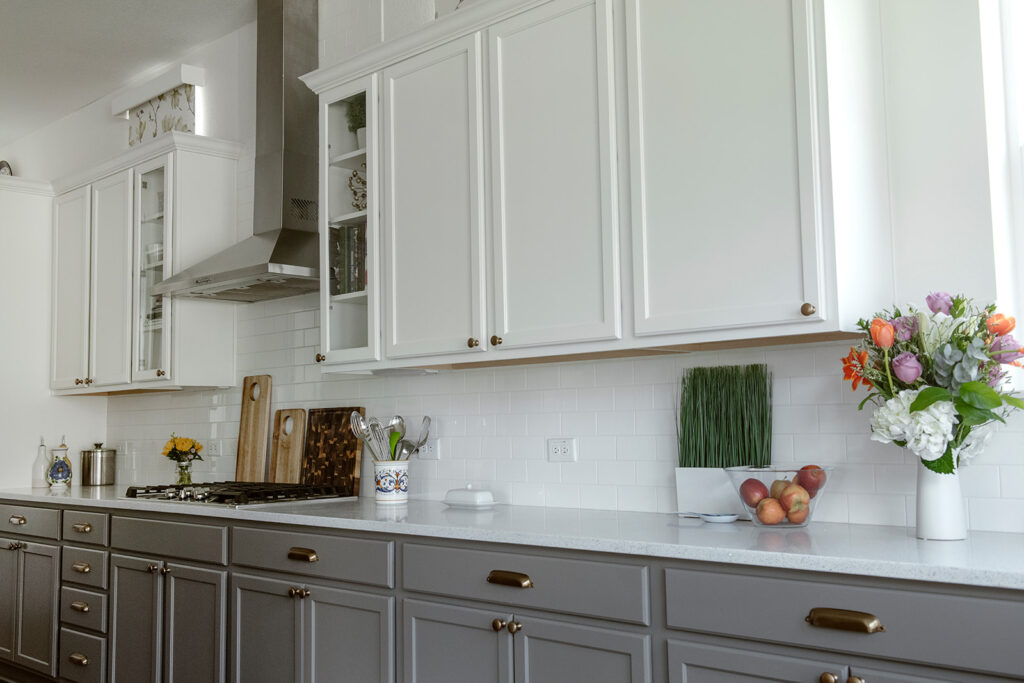 A kitchen features tuxedo kitchen cabinets with BM Chelsea Gray lowers and SW Pure White upper cabinets.