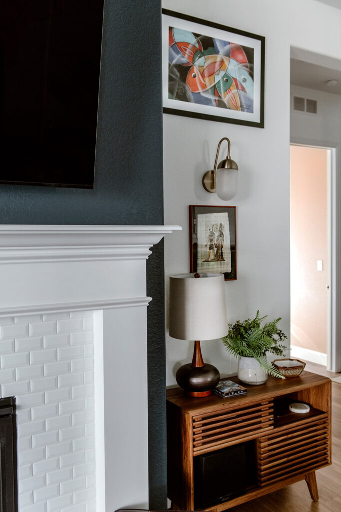 A living room is painted with BM Simply White walls and a SW Cyberspace fireplace accent wall.