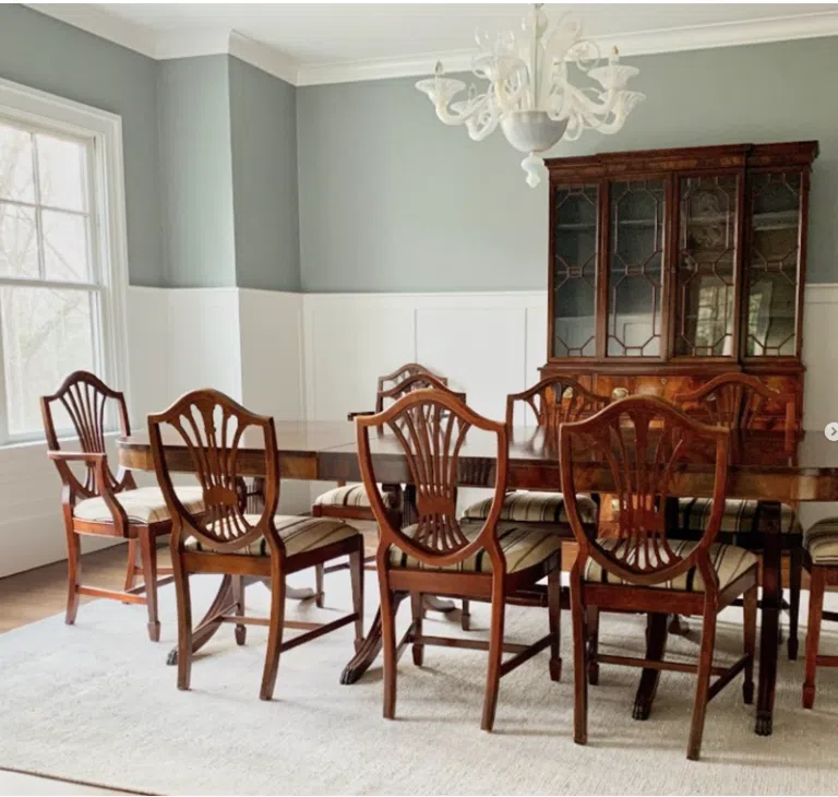 A dining room is painted with BM Boothbay Gray and white wainscoting.