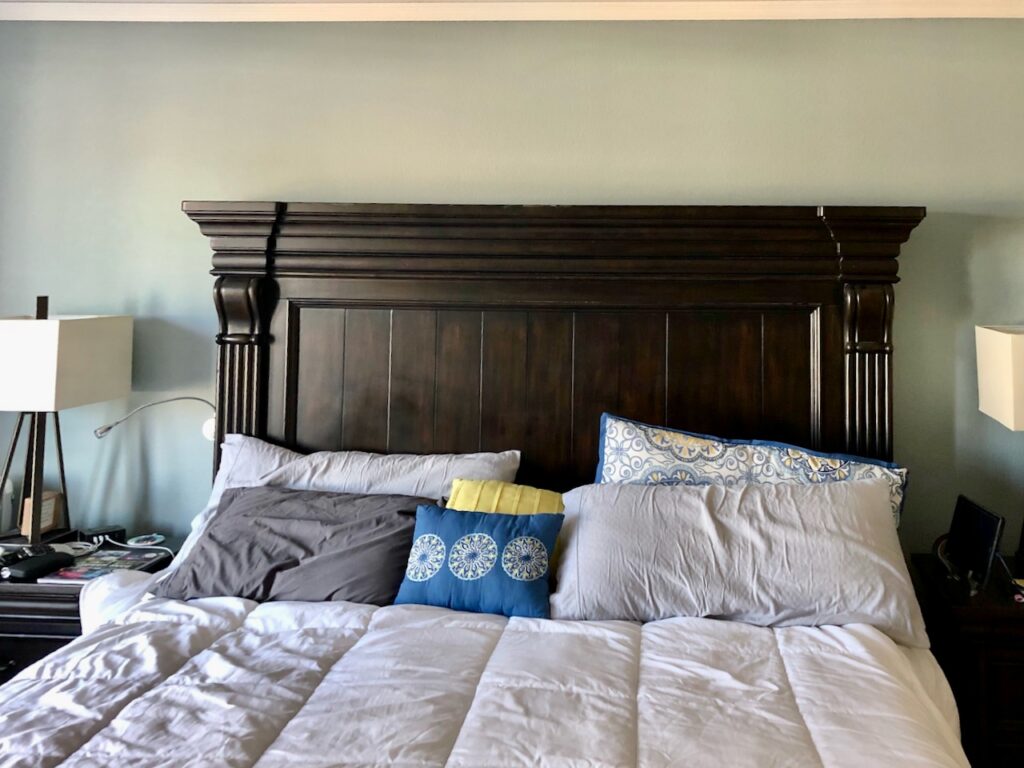 A bedroom is painted with BM Mount Saint Anne and features a dark wood headboard. 